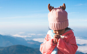 Cute asian child girl wearing sweater and warm hat making folded